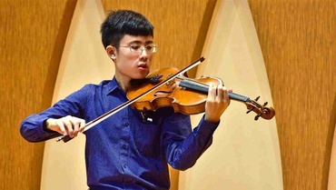 He-Yuan Cheng spielt vor einer holzvertäfelten Wand Geige