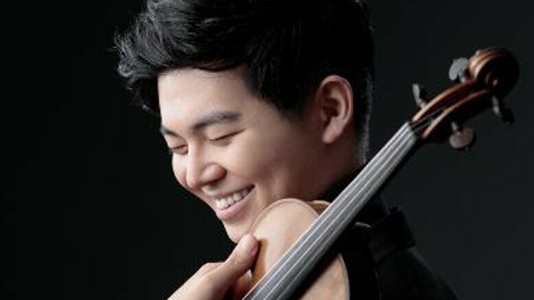 Jiho Kang steht mit Geige vor einem schwarzen Hintergrund