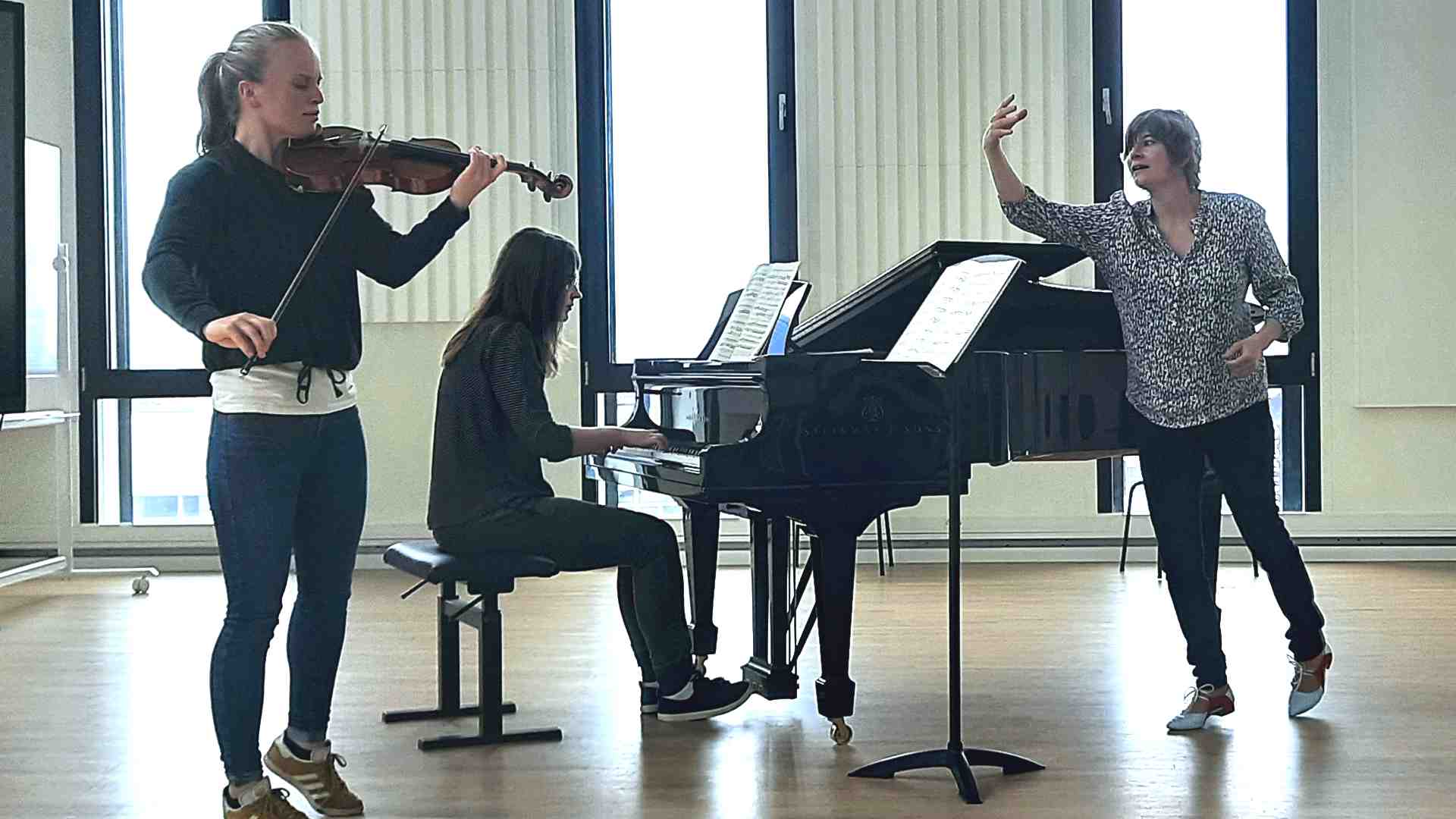 Violinistin und Pianist spielen, Mentorin gibt Anweisungen
