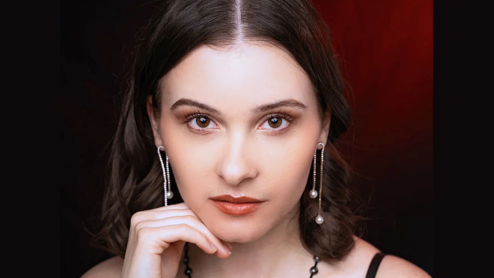 Verena Seyboldt in einem schwarzen Abendkleid vor einem roten Hintergrund