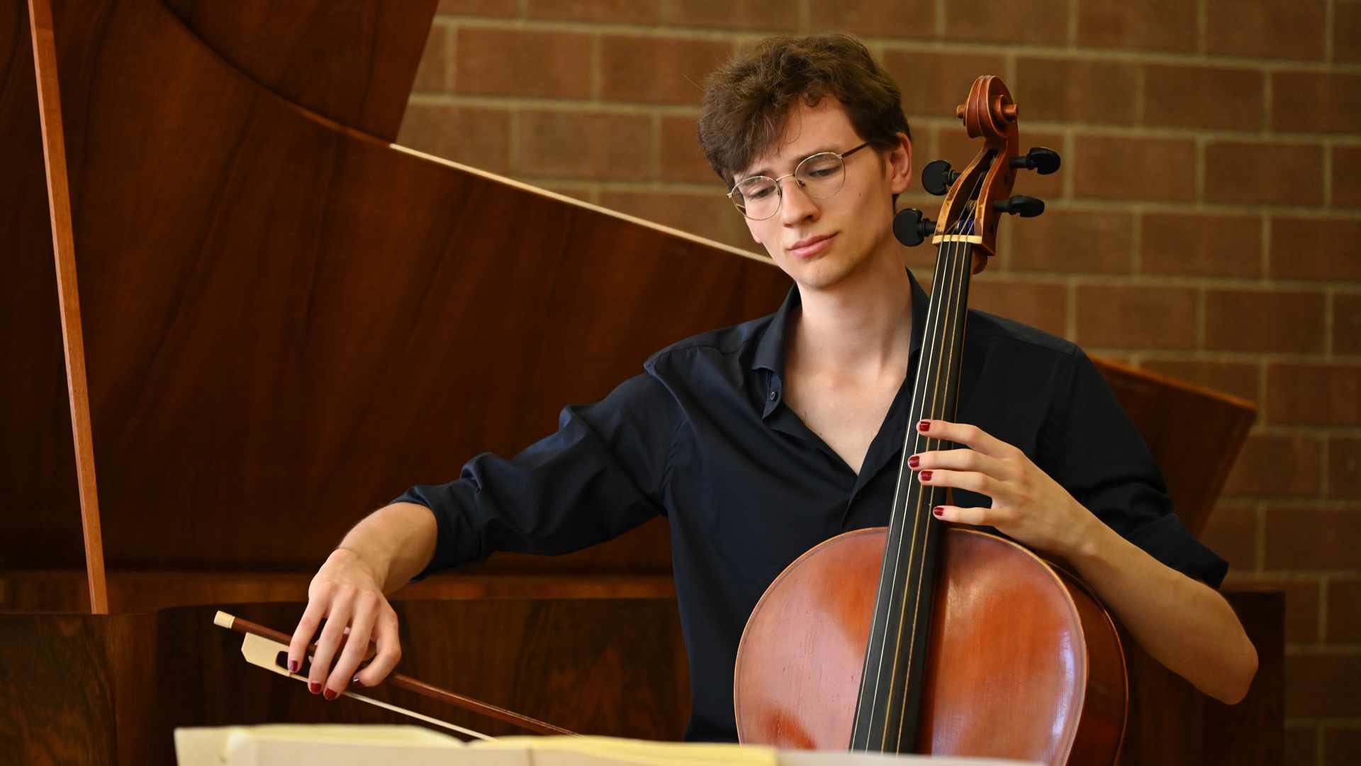 Gian-Andri Cuonz in schwarzer Kleidung spielt Cello auf einer Konzertbühne