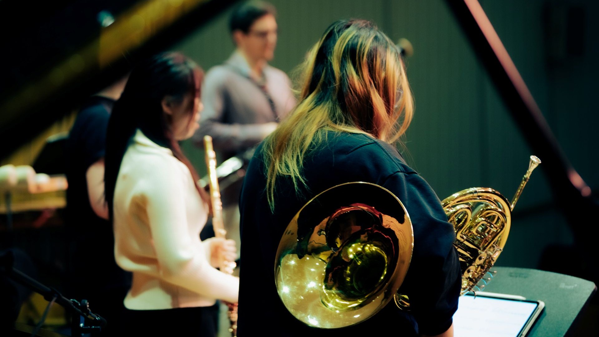 Flötistin, Fagottist und Hornistin auf der Bühne schräg von hinten