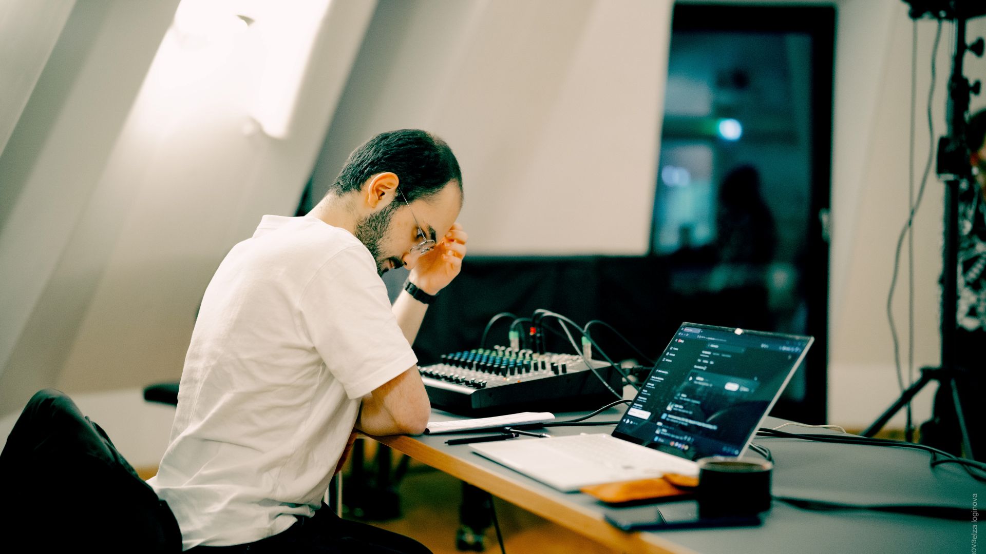 İlyas Talha Güneş am Regietisch vor Mischpult und Laptop seitlich leicht von hintenvon 