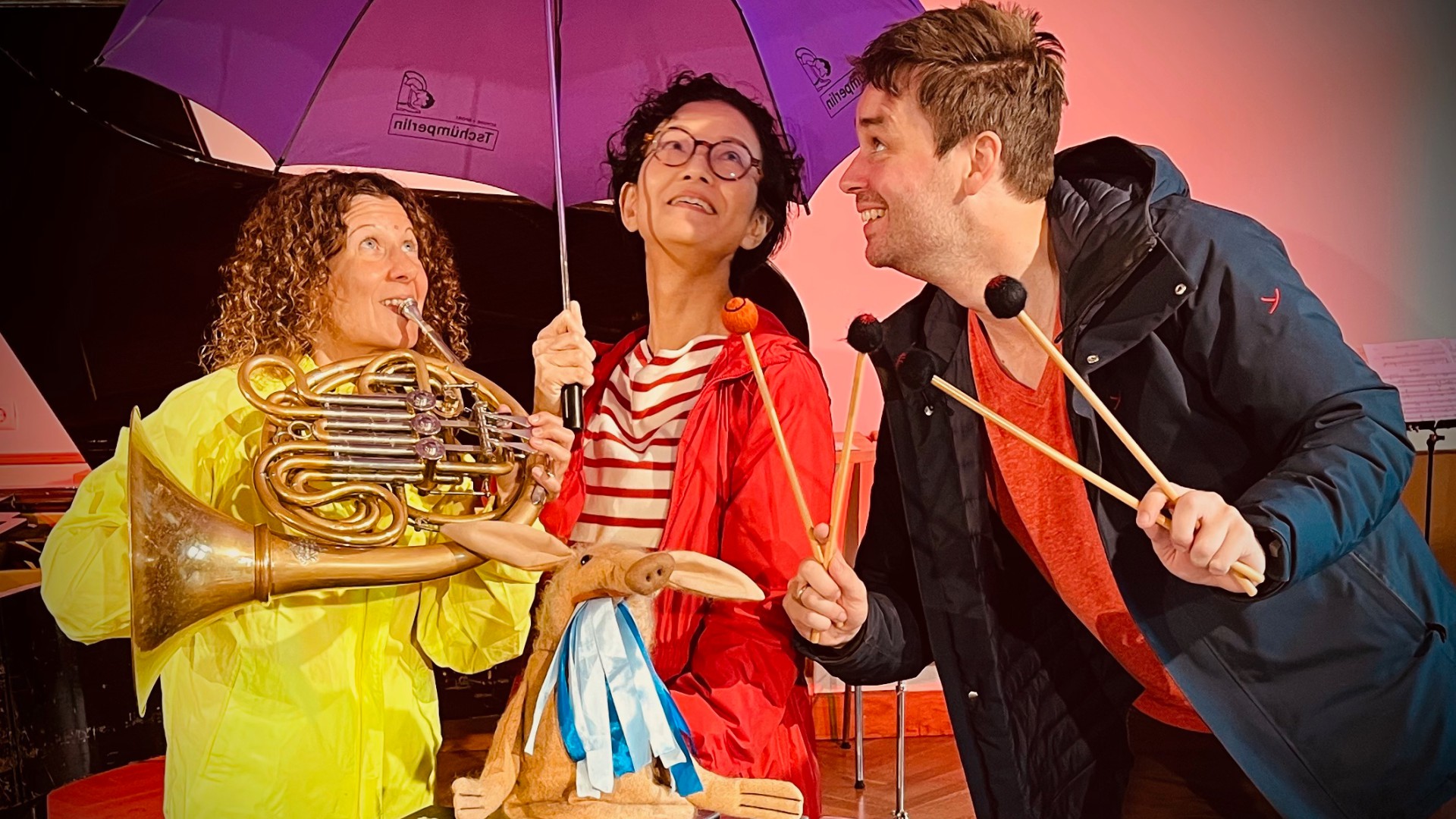 Drei Musiker: Einer mit Schlagstöcke, eine mit einer Tuba und eine mit einem Schirm