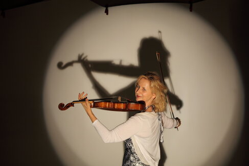 Diemut Poppen spielt auf einer Bühne im Kegel des Scheinwerferlichts