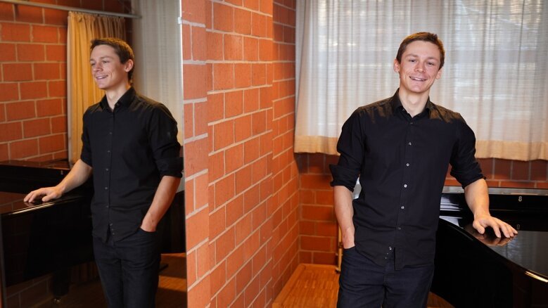 David Klüglich in einem Überaum der Hochschule vor einem Flügel