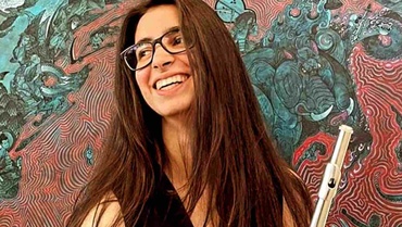 Sara Vázquez Sanz steht mit Querflöte in der Hand vor einer bunten Wand