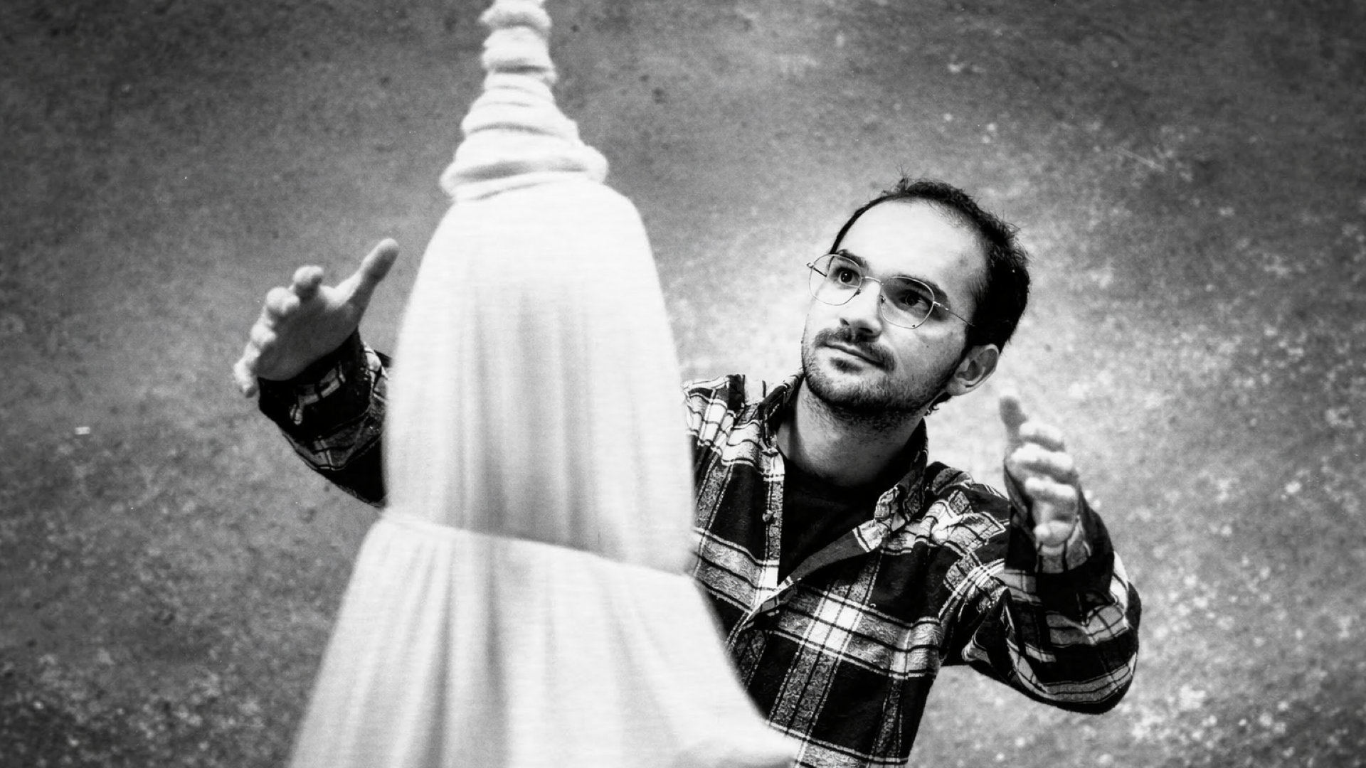 İlyas Talha Güneş seitlich hinter der Figur eines tanzenden Derwischs, zu der er die Arme hochreckt