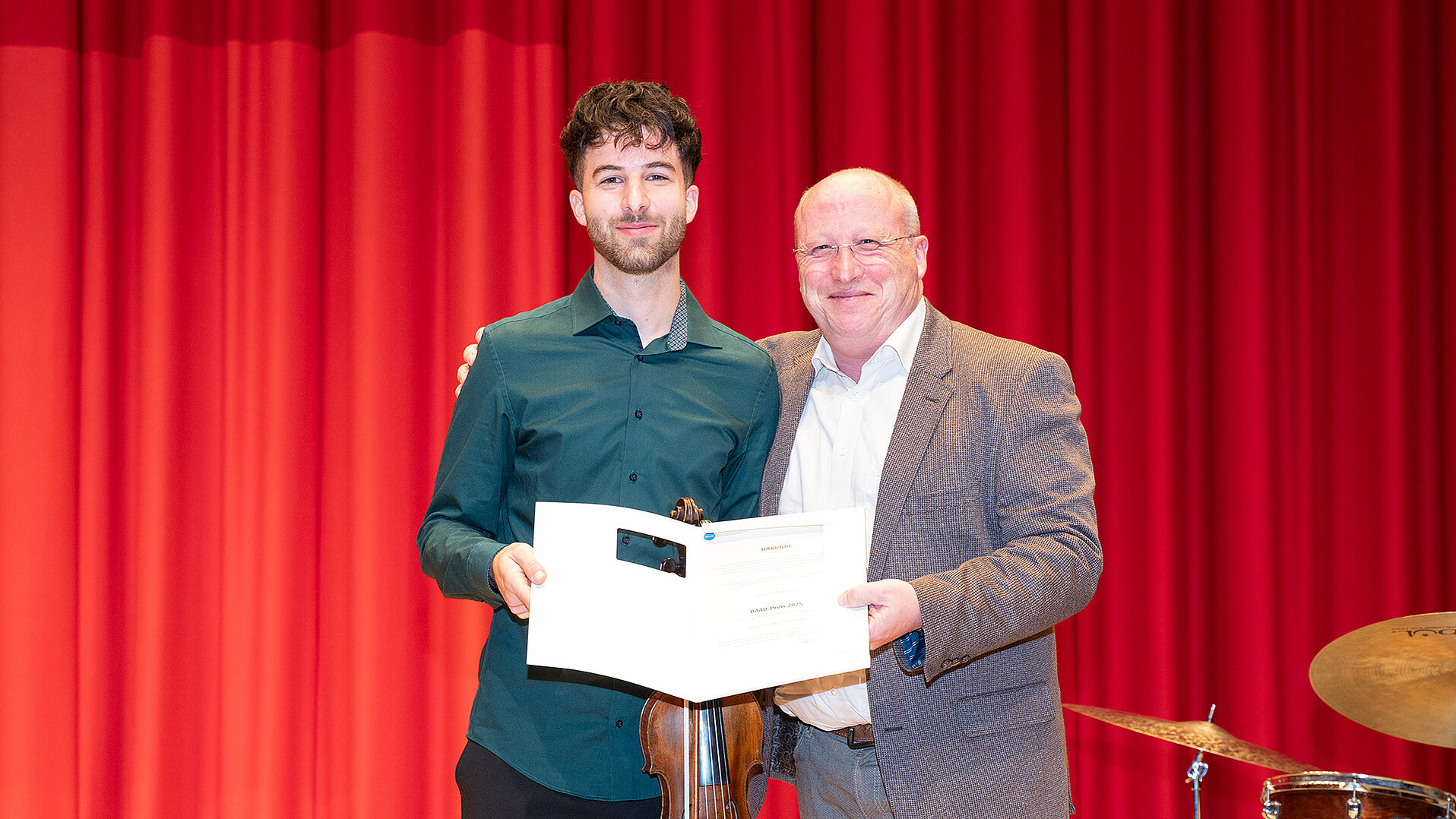Scott Sandmeier überreicht Simone Schermi seine Urkunde auf der Bühne des Konzertsaals