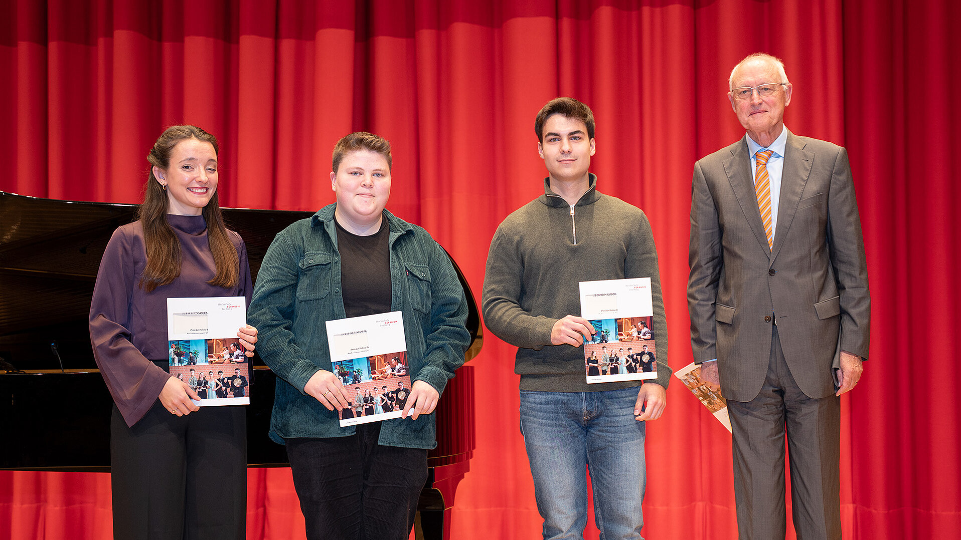 Theresa Bertrand, Anna Schote, Mihai Goncearuc und Michael Krenzler stehen mit Urkunden in den Händen auf der Bühne des Konzertsaals