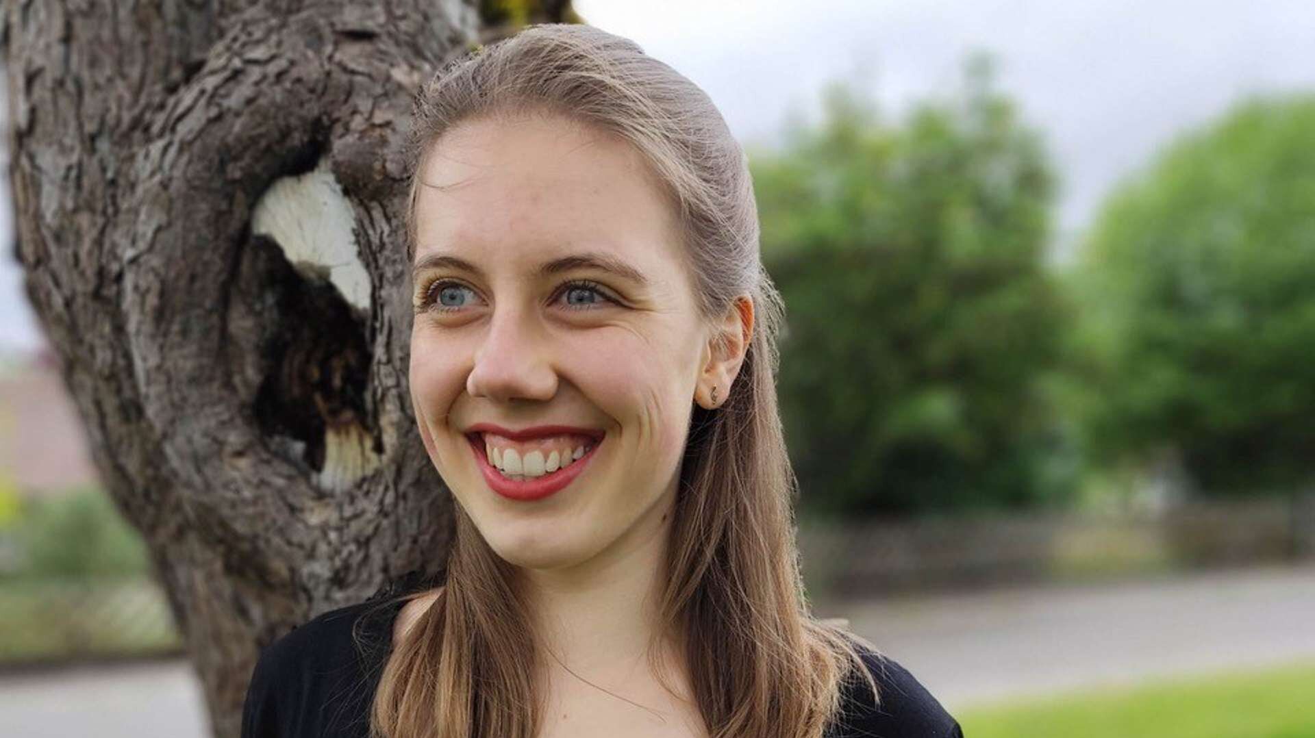 Magdalena Schmucker steht in einem schwarzen Shirt vor einem Baum