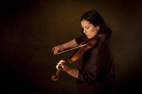 Cecilia Bercovich spielt Viola vor einem dunklen Hintergrund