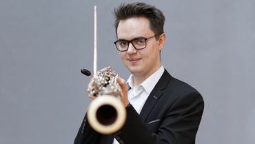 Carl Roewer mit Fagott in der Hand vor grauem Hintergrund