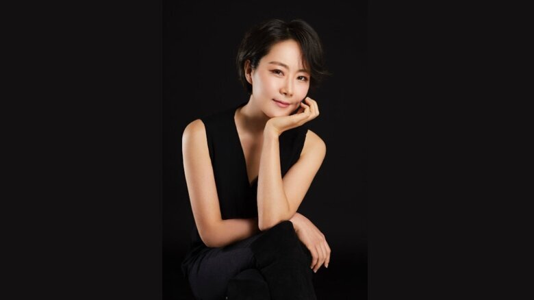 Kumi Choi in einem schwarzen Kleid vor einem schwarzen Hintergrund