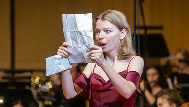Eine Sängerin schaut überrascht auf ein Blatt Papier