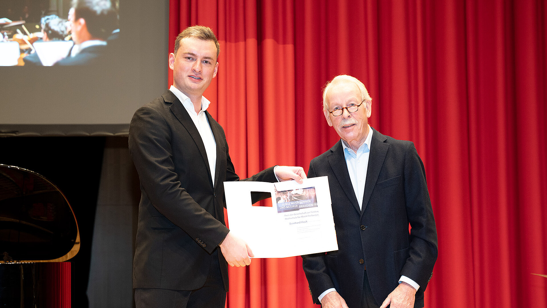Ulrich Keller überreicht Bernhard Hauk seine Urkunde auf der Bühne des Konzertsaals