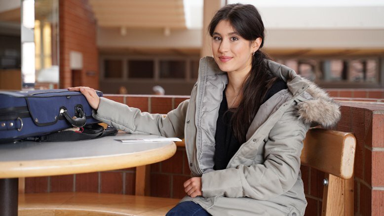 Die Studentin Mathilda Dendorfer sitzt auf einer Bank im Foyer der Musikhochschule