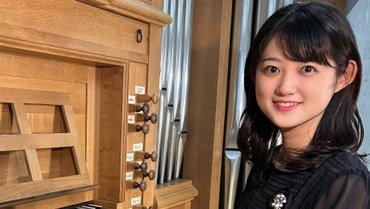 Risa Toho sitzt vor einer Orgel und schaut in die Kamera