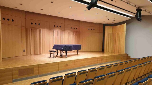 Der Kammermusiksaal der Hochschule, mit leeren, blauen Sitzen und einem eingepackten Flügel auf der Bühne