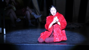 Sängerin in roter Robe sitzt auf dem Boden der Bühne
