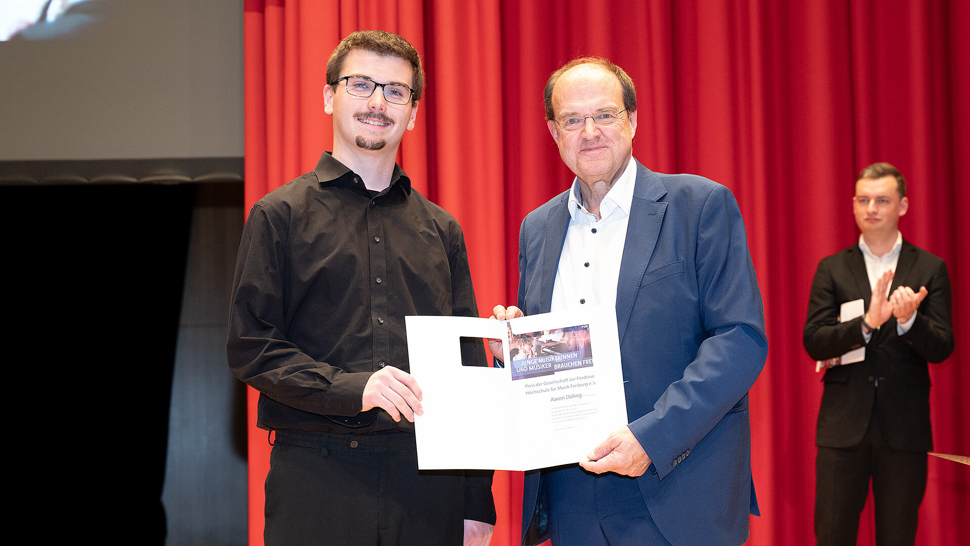 Ludwig Holtmeier überreicht Aaron Döling seine Urkunde auf der Bühne des Konzertsaals