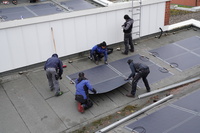 Arbeiter kleben die PV-Platten auf dem Dach auf