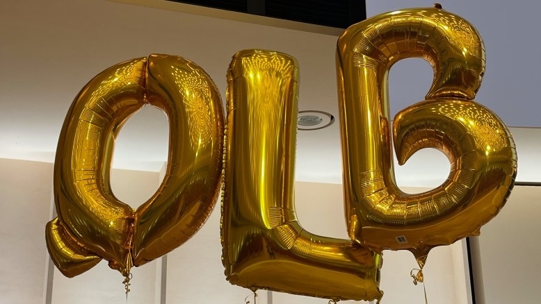 Drei goldfarbene Luftballons mit den Buchstaben QLB